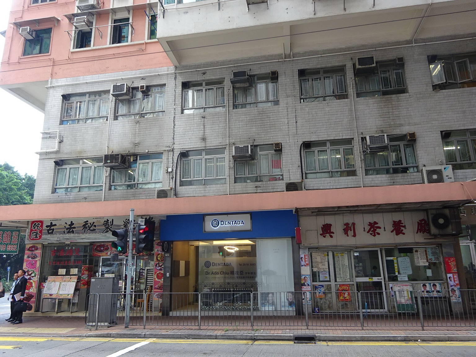 香港堅尼地城 Belcher 街的普通城市街景，沿街公寓、新建住宅和树木组成与保单现金流相关的日常生活背景。